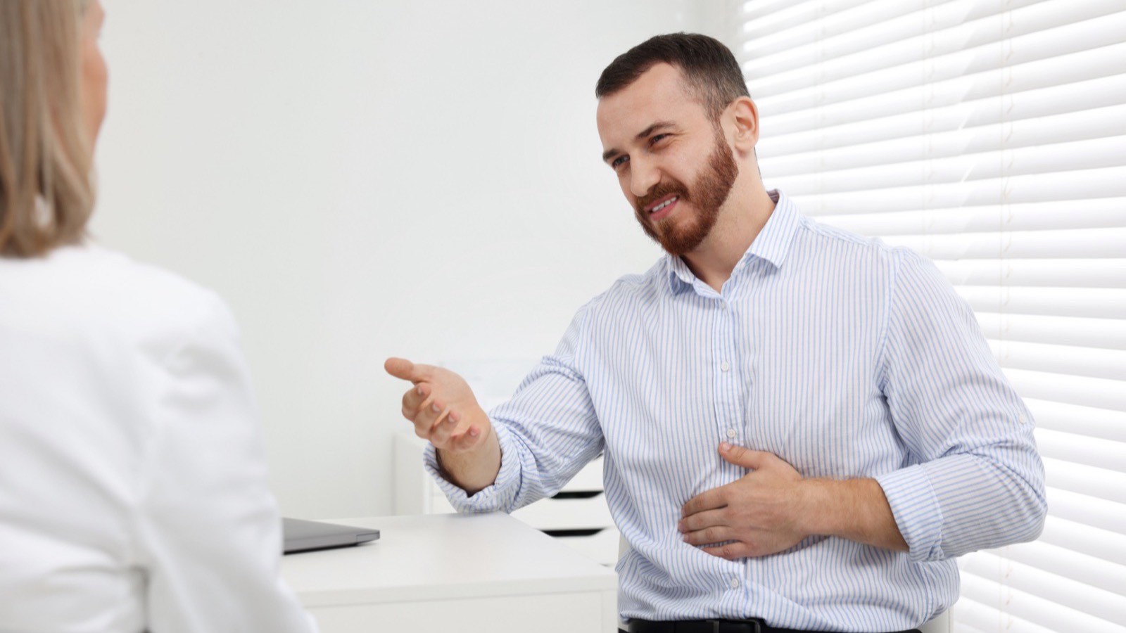 Médico explicando o resultado de uma endoscopia digestiva a um paciente em consultório